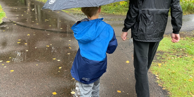 Grandfather & grandson walking in the rain.